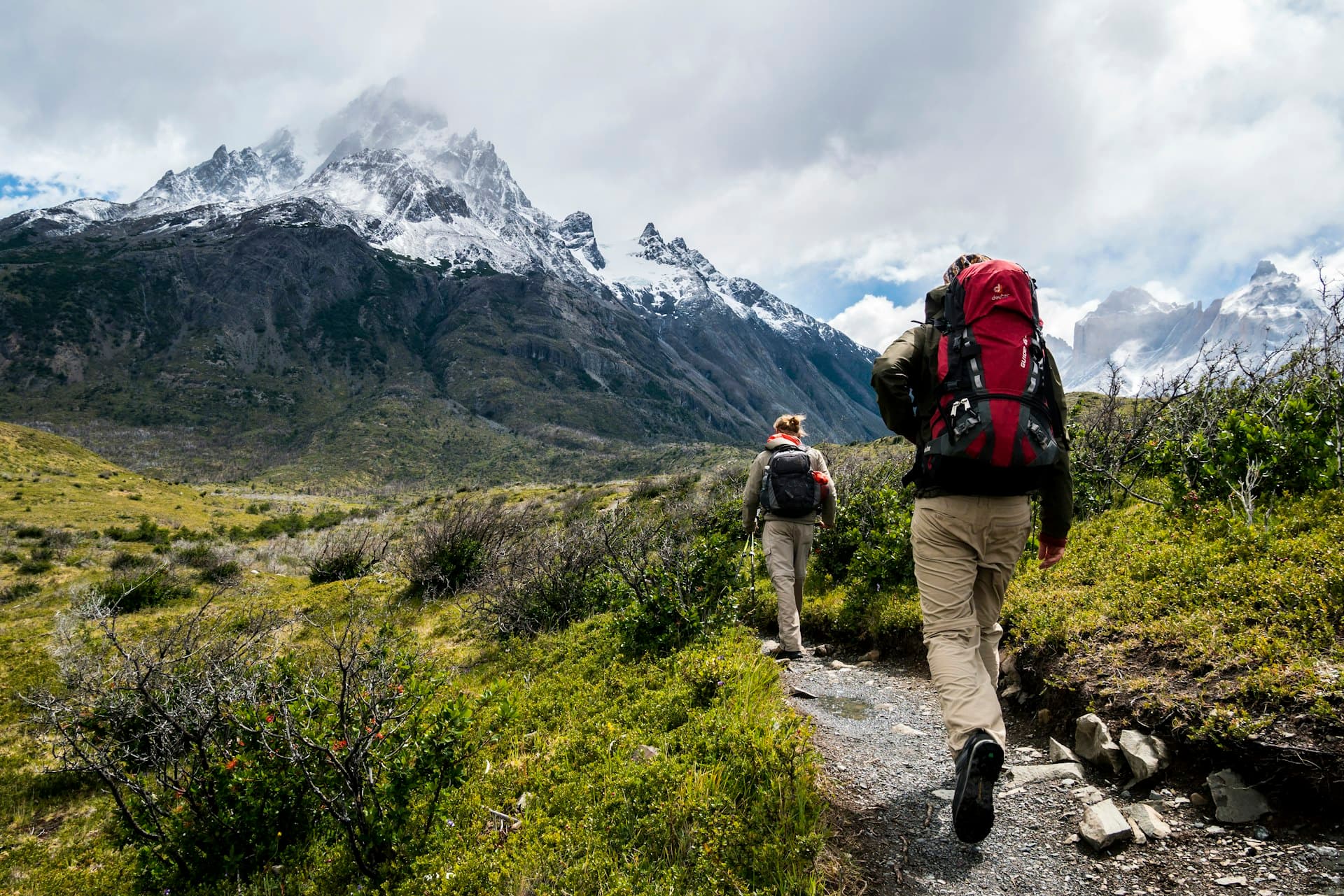 Hikers crossing a high ridge above a glacial valley.