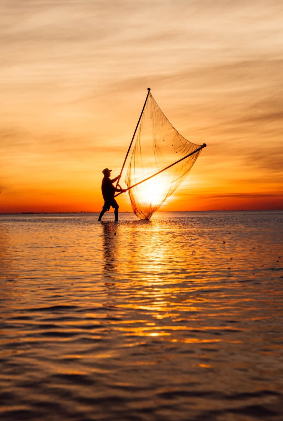 A fisherman casting a net at sunset on the Tonle Sap.